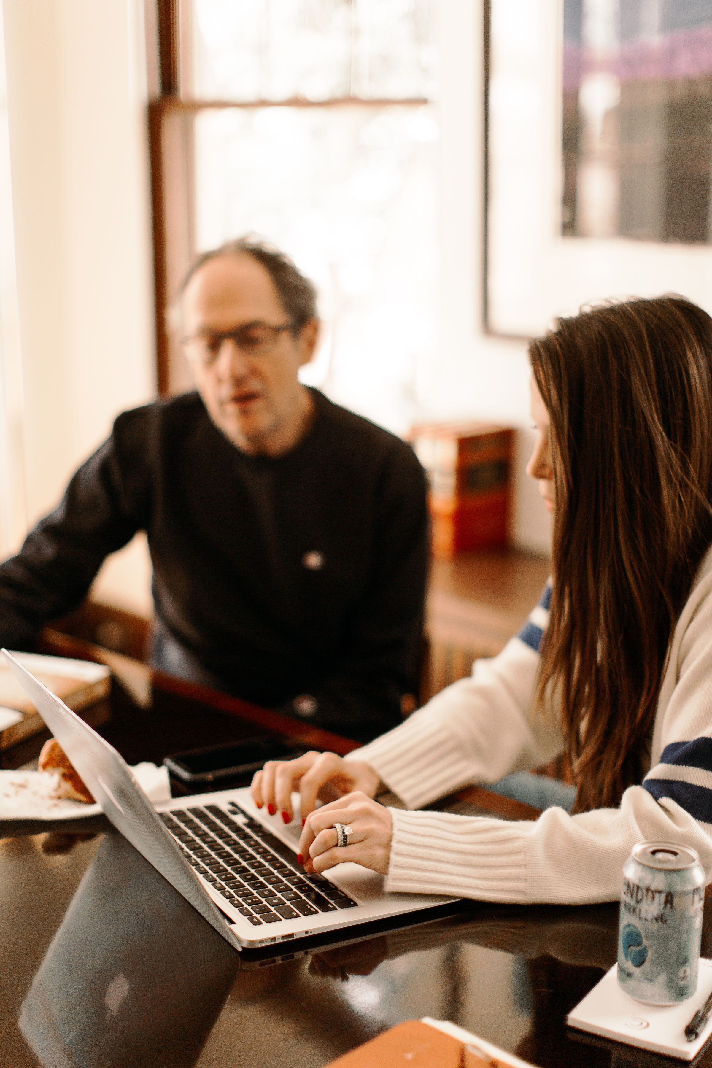 two people looking at a laptop screan while the one person types.